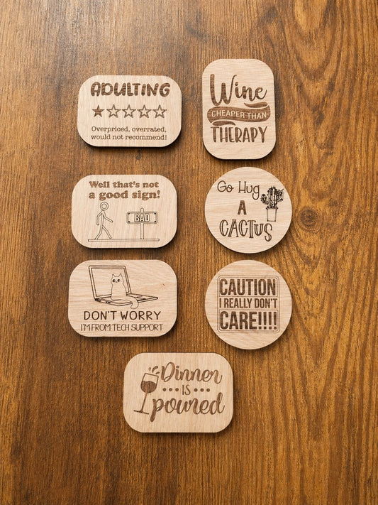 Set of wooden coasters with humorous sayings on a wooden surface