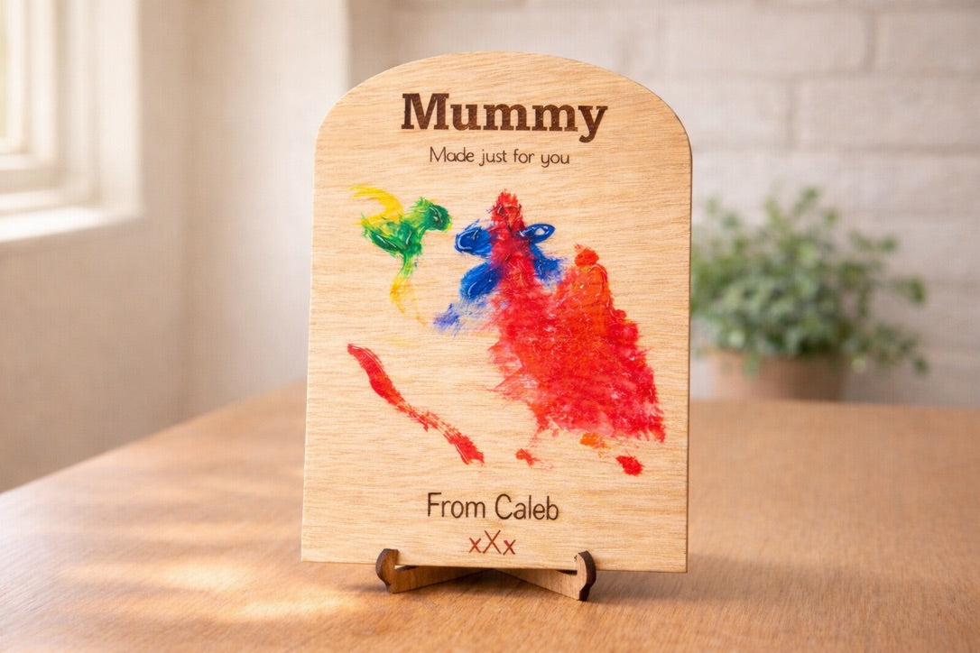 Wooden plaque with colorful handprints and text on a table